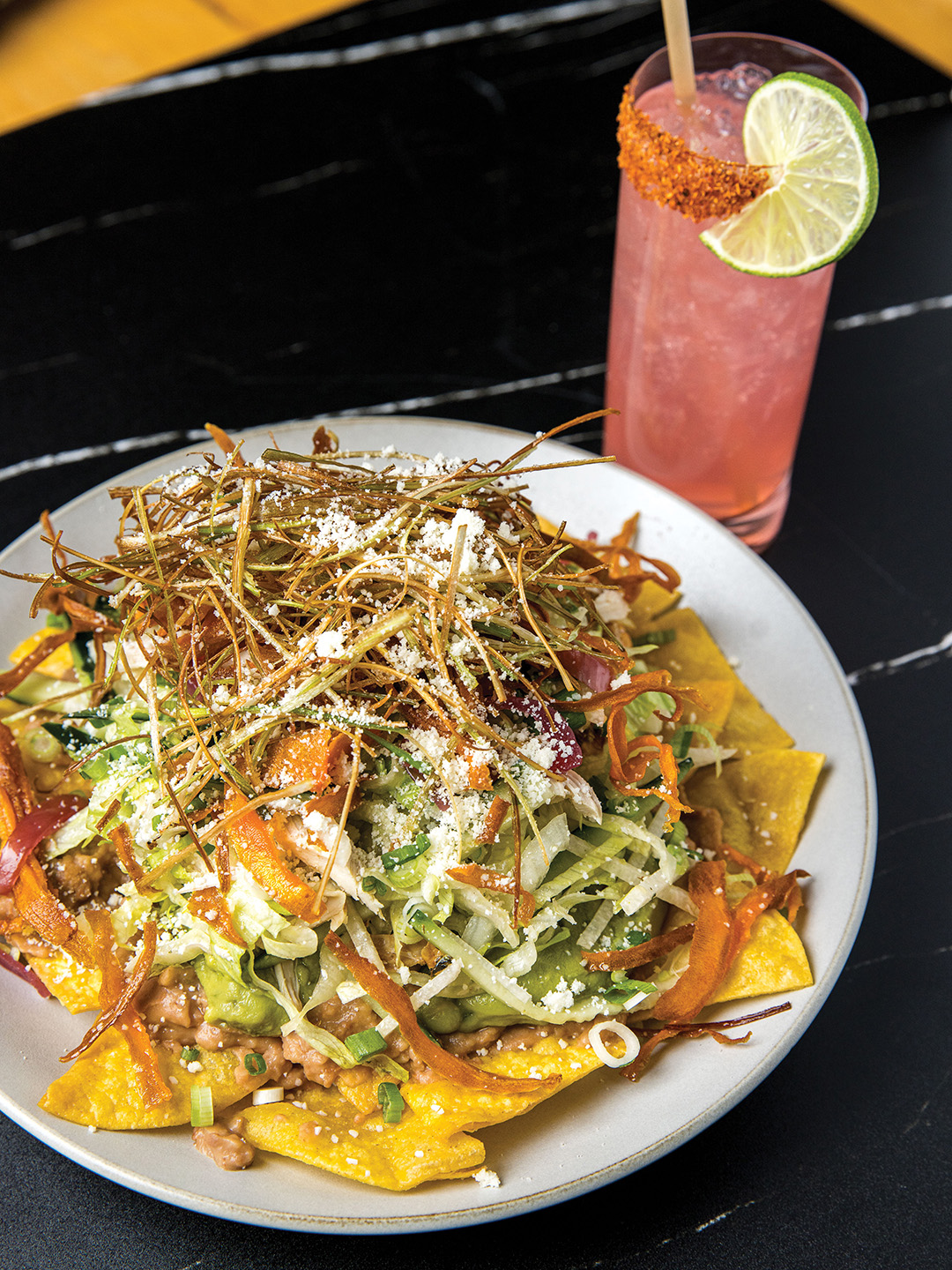 The hearty Topopo Salad includes pulled chicken, refried beans, tortilla chips, guacamole, shredded lettuce, fried leeks and carrots, jicama, cucumber, scallion, Mexican oregano, oil and vinegar.